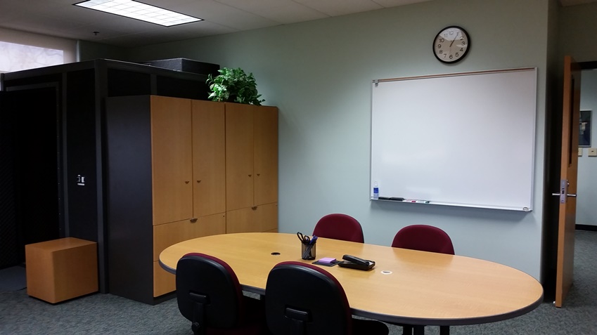 View of the whiteboard, conference table, recording booth, and back cabinets in 1253B.